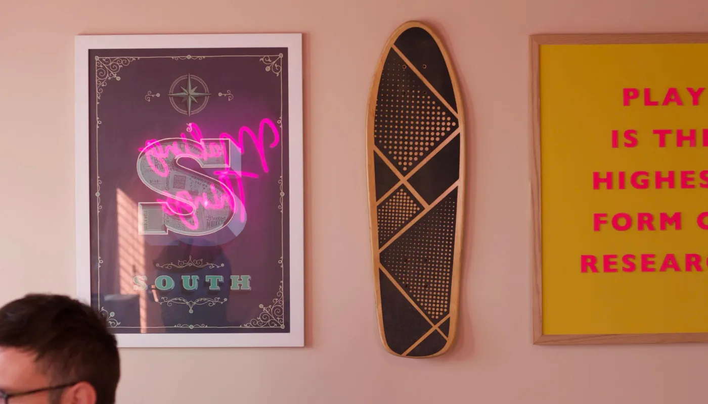 The studio wall: a Southsea print, a skateboard, and the sign that says play is the highest form of research